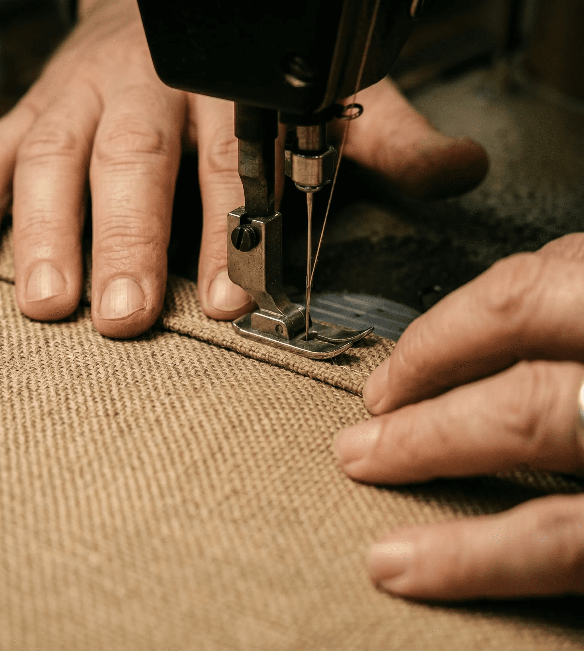 Hands guiding canvas material through a sewing machine